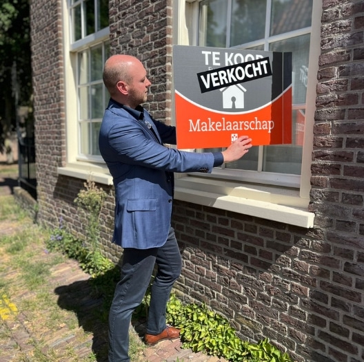 Makelaar van Makelaarschap plaatst een verkocht-bord bij een woning in Elburg